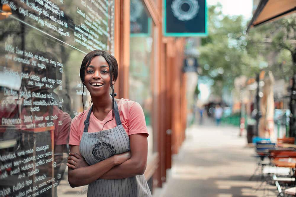 Barista crossing arms outside shop