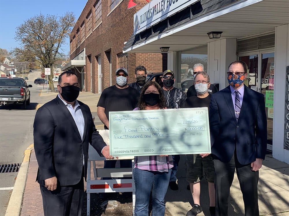 People giving a large-sized check to food pantry outside 